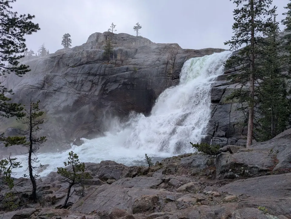 Grande cascade dévalant une falaise rocheuse entre les pins