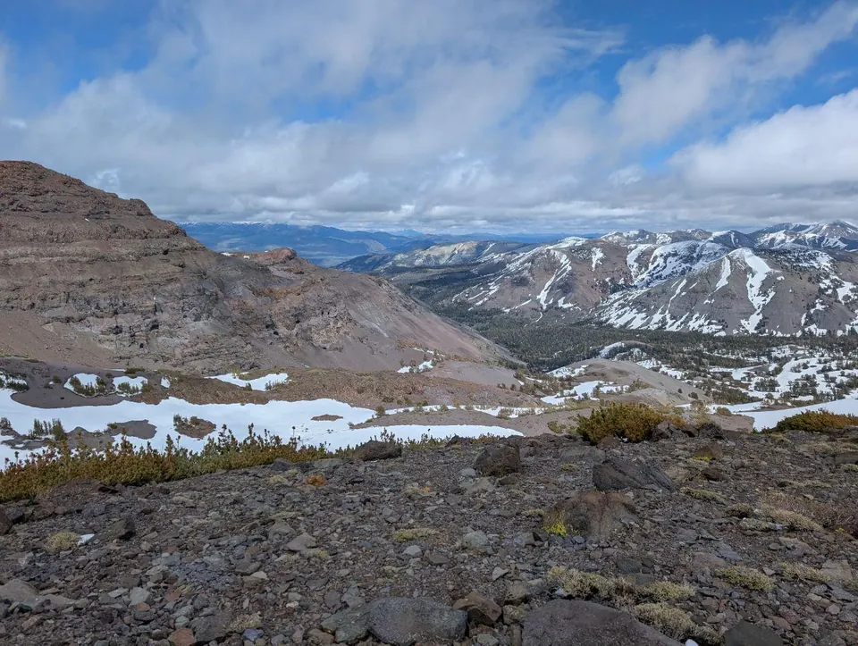 Vallée aride et sommets saupoudrés de neige sous les nuages