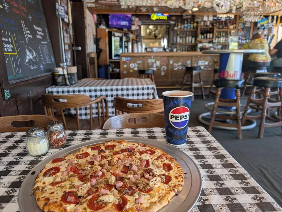 Pizza et gobelet de soda servis sur une table de restaurant