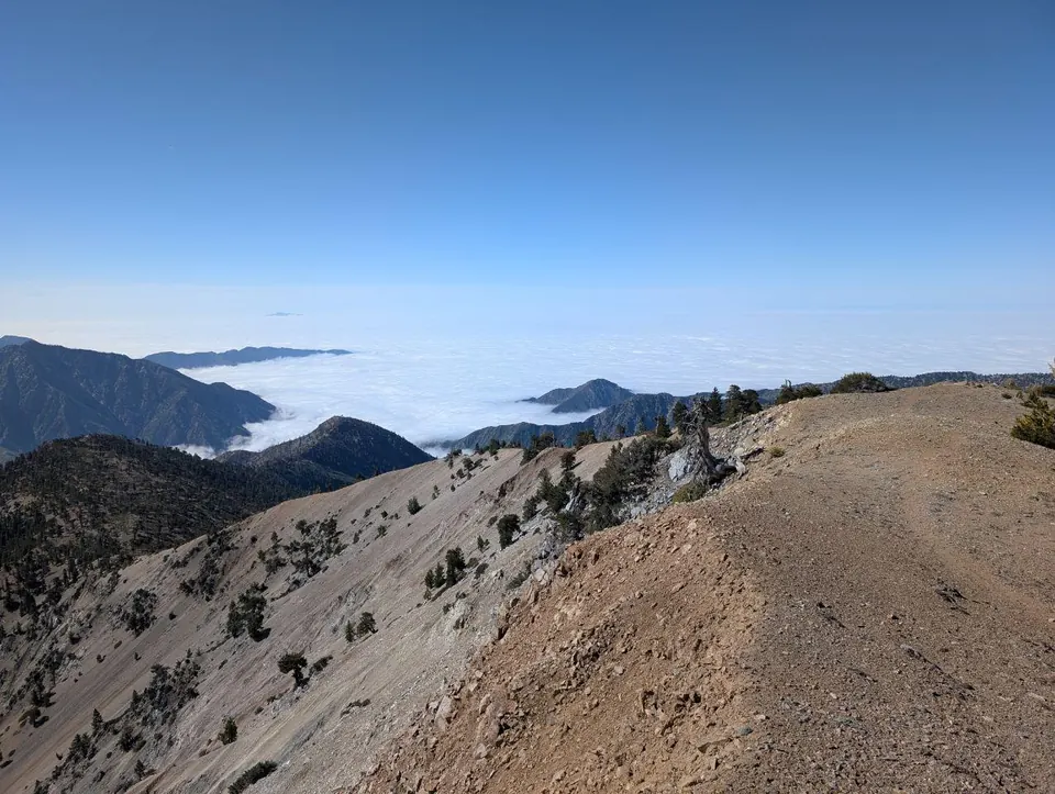 Crête minérale dominant une mer de nuages entre les montagnes