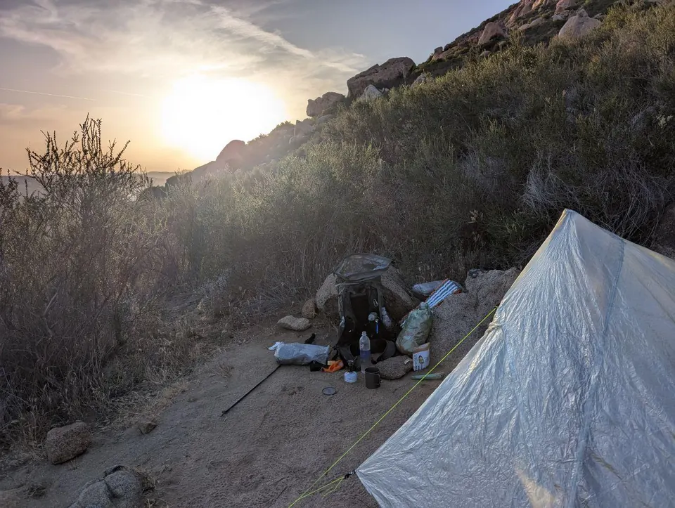Campement léger installé sur un versant aride au coucher du soleil