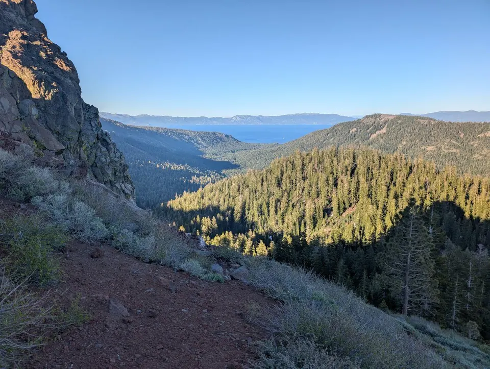 Vallée boisée ouvrant sur un lac bleu au loin