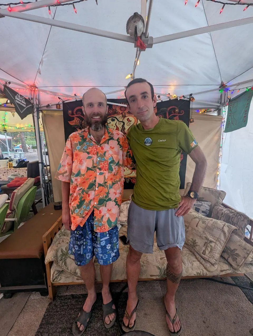 Deux hommes posant sous un abri décoré de fanions