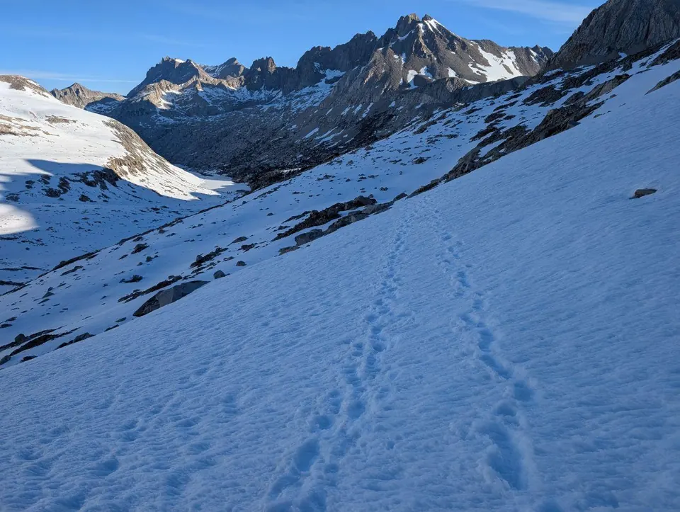 Traces de pas traversant une pente enneigée sous une crête déchiquetée