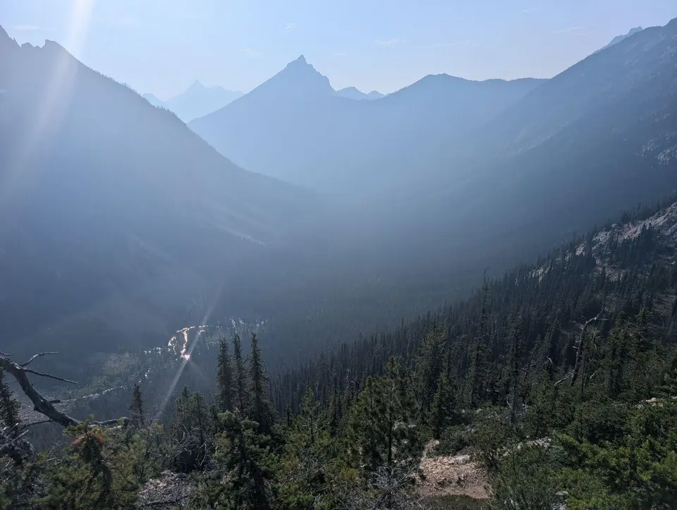 Vallée montagneuse noyée dans la brume et traversée par un rayon de soleil