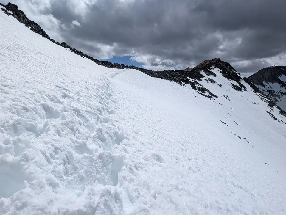 Pente de neige marquée de traces sous un ciel d'orage