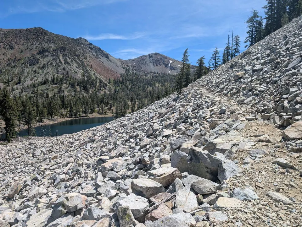 Pierrier abrupt descendant vers un petit lac de montagne