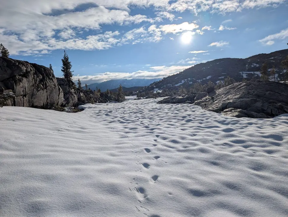 Traces de pas dans la neige entre de grandes dalles rocheuses