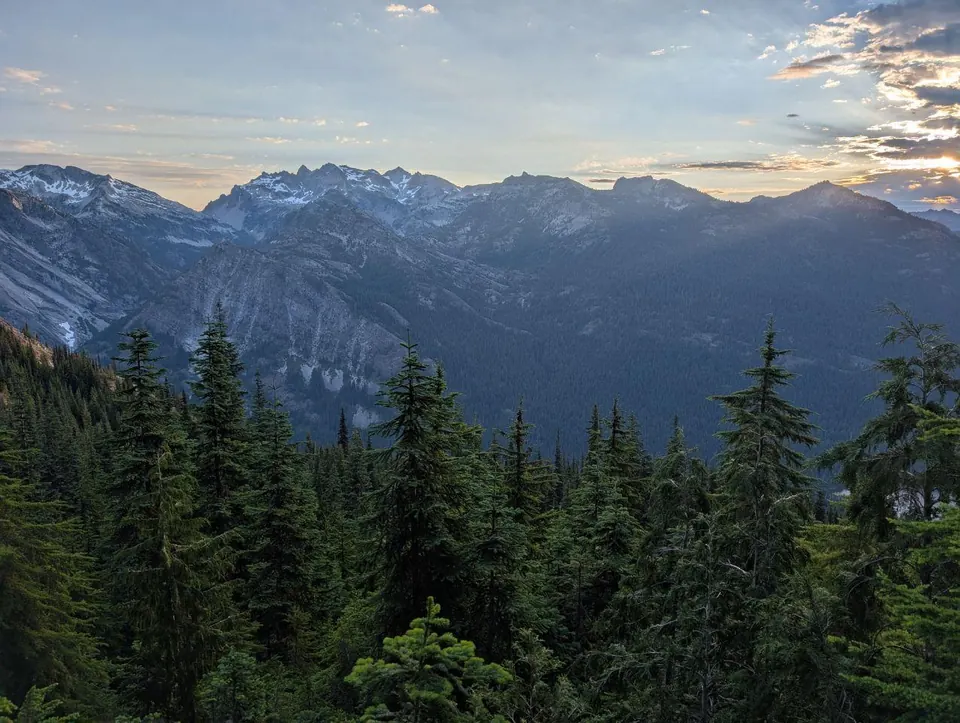 Chaîne de montagnes boisées sous un ciel de fin de journée