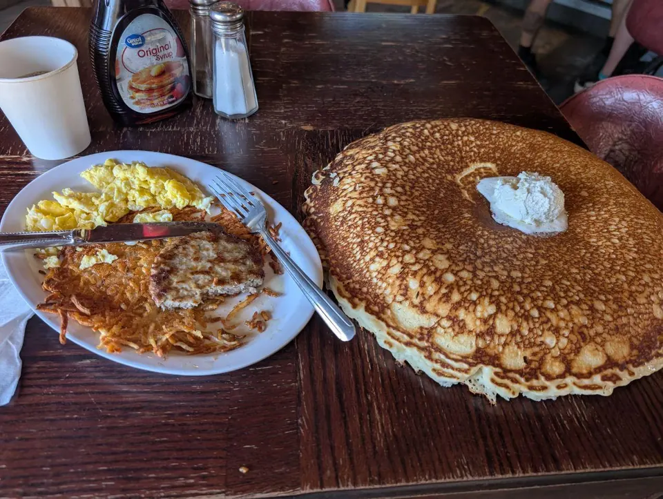 Petit-déjeuner composé d'une grande pile de pancakes, d'œufs et de pommes de terre