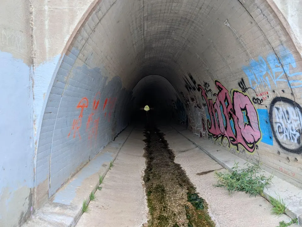 Long tunnel en béton couvert de graffitis