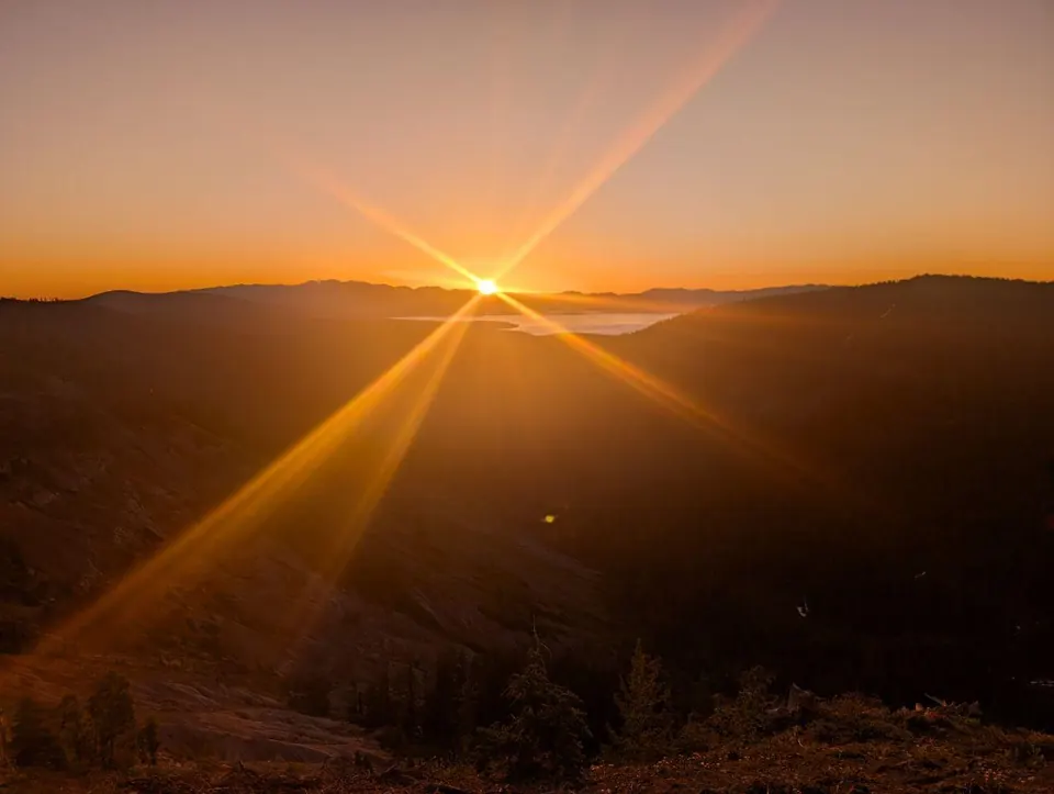 Soleil couchant au ras de collines sombres