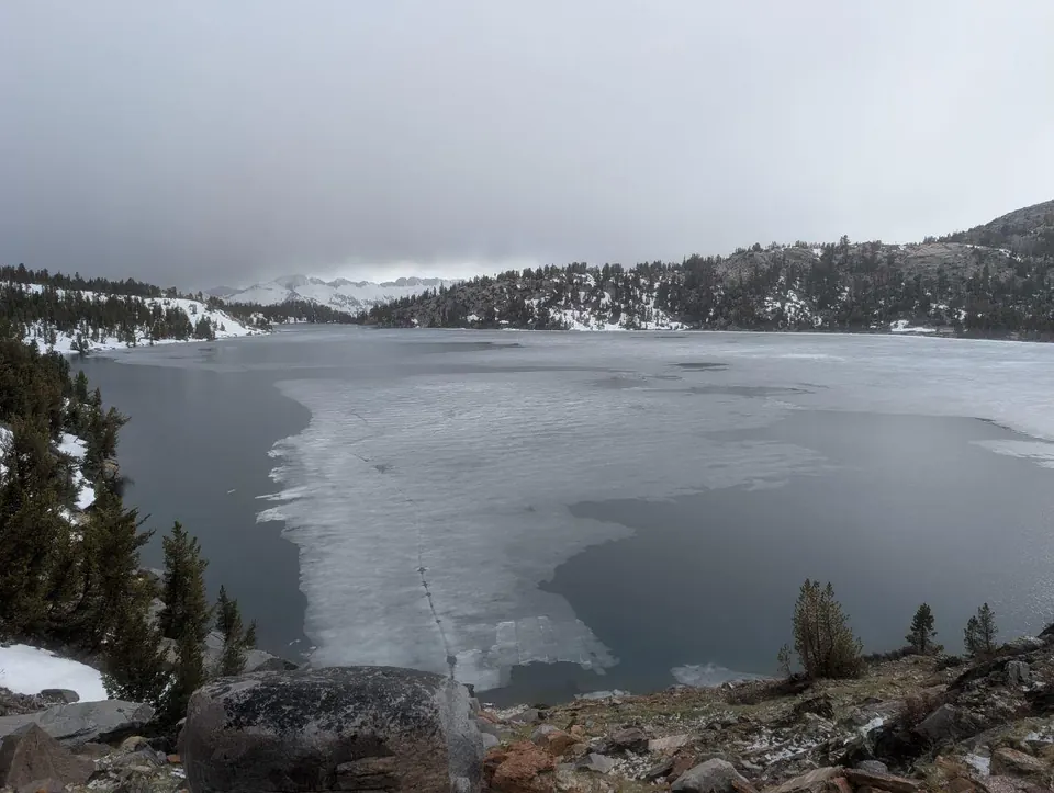 Lac partiellement gelé sous la brume et la neige