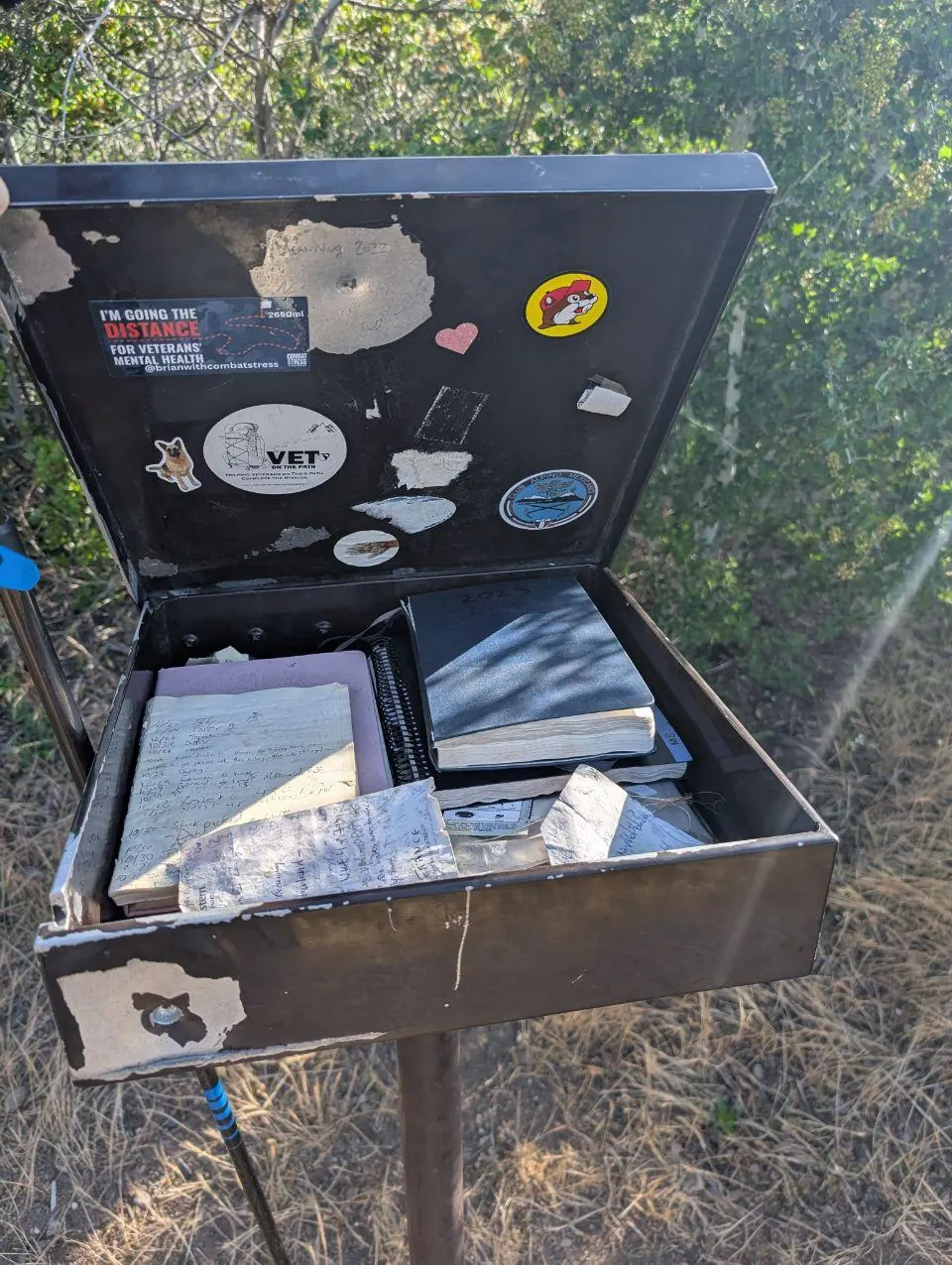 Boîte de registre de randonnée ouverte avec carnets et messages