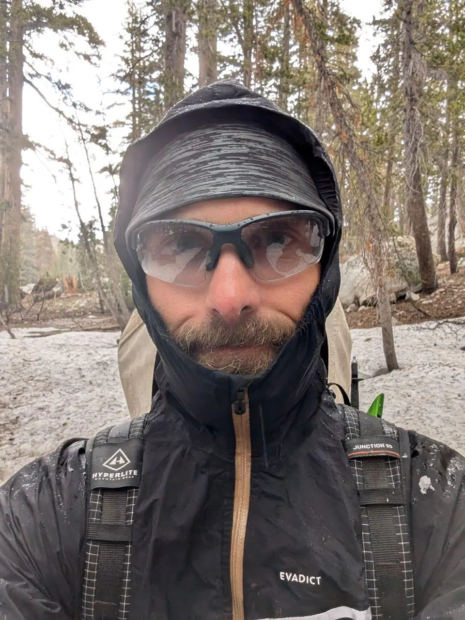 Randonneur emmitouflé avec lunettes sous une chute de neige