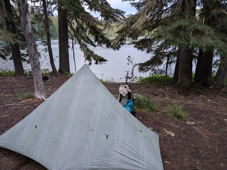 Tente légère dressée sous les arbres au bord d'un lac