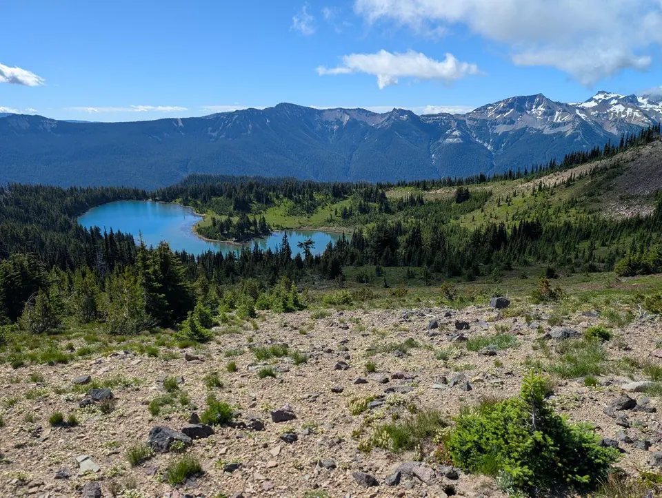 Lac alpin bleu entouré de montagnes encore enneigées