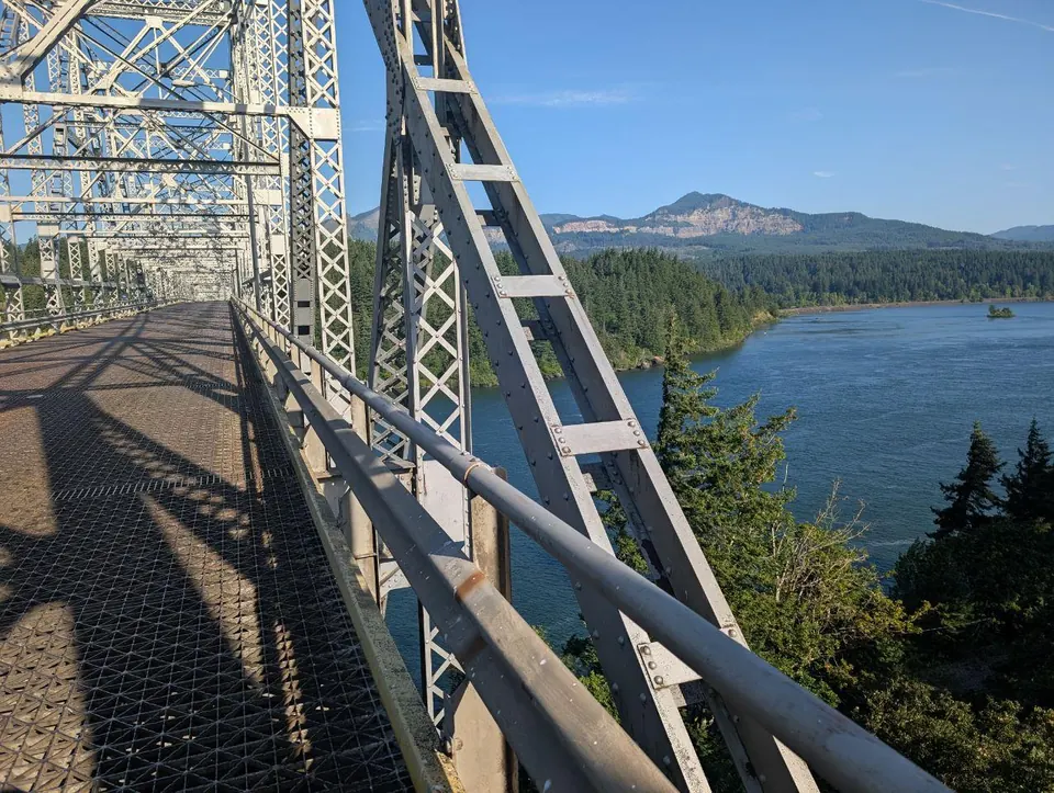 Passerelle métallique dominant un lac bordé de montagnes
