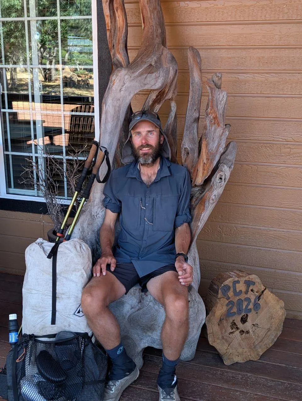 Randonneur assis avec son sac devant un bâtiment en bois sculpté