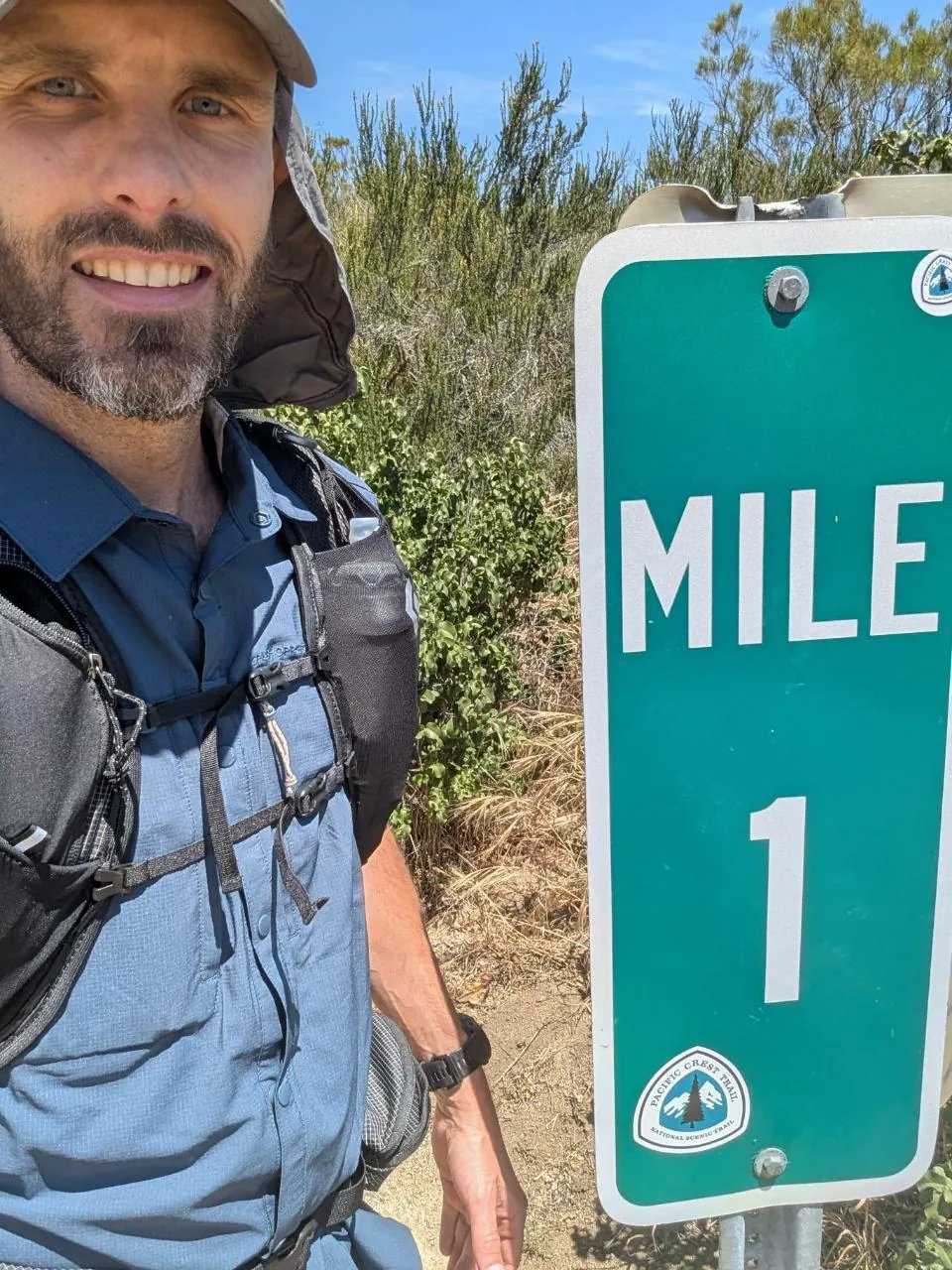 Randonneur souriant à côté du panneau Mile 1