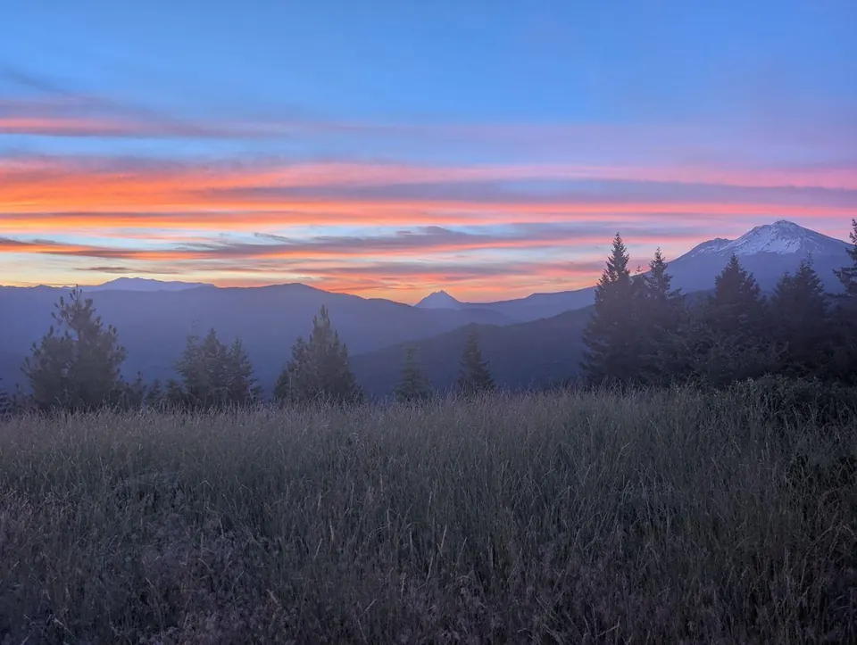 Ciel rose et orange au-dessus de silhouettes montagneuses