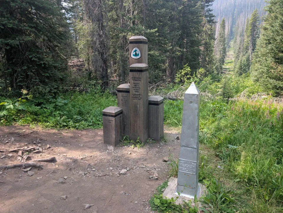 Monument du terminus nord du Pacific Crest Trail au milieu de la forêt