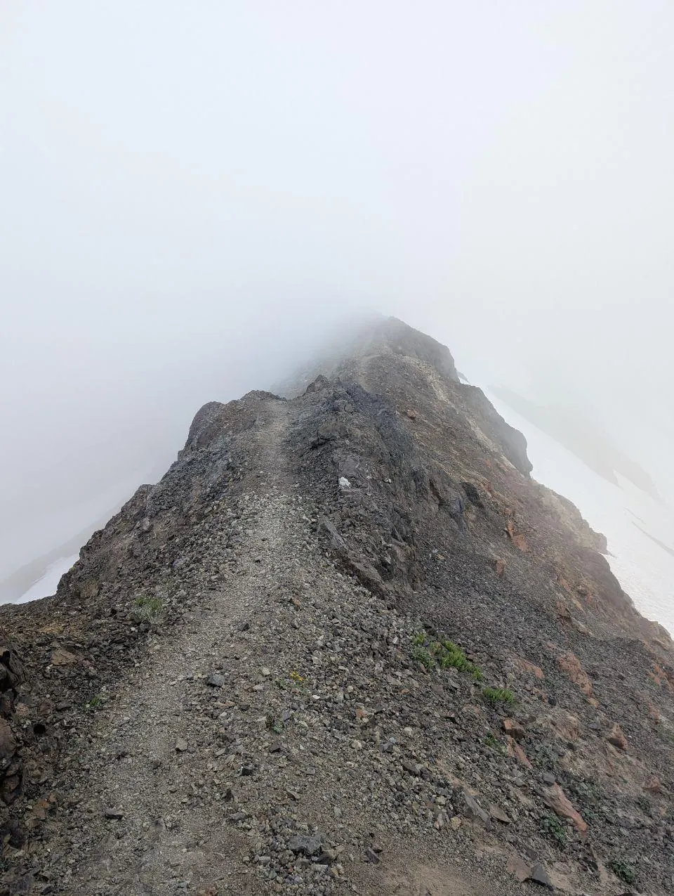 Arête rocheuse disparaissant dans un brouillard dense