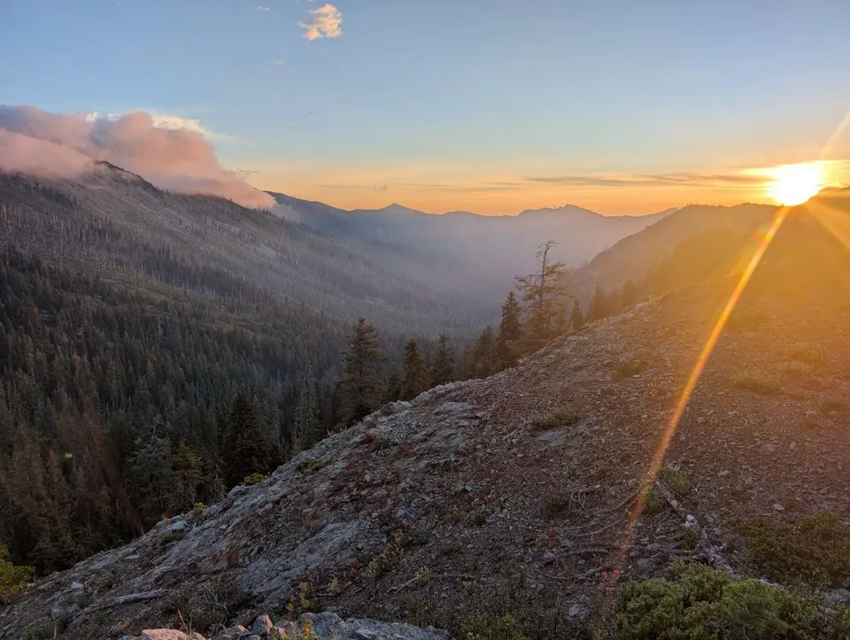 Soleil levant sur des montagnes partiellement noyées dans la fumée