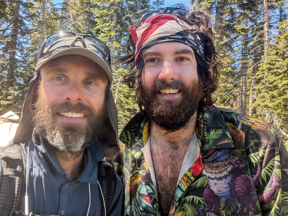 Deux randonneurs barbus souriant dans une forêt
