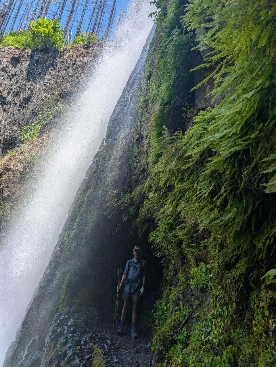 Randonneur debout derrière une haute cascade