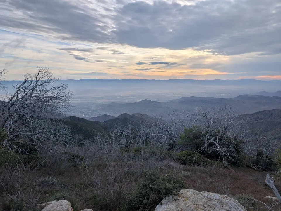 Coucher de soleil derrière des montagnes couvertes de broussailles