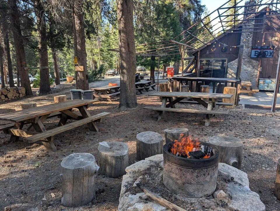 Feu allumé devant les tables d'un refuge en forêt