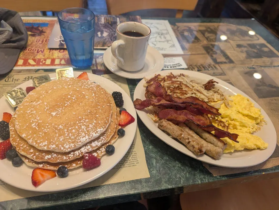 Petit-déjeuner composé de pancakes, œufs, bacon et saucisses