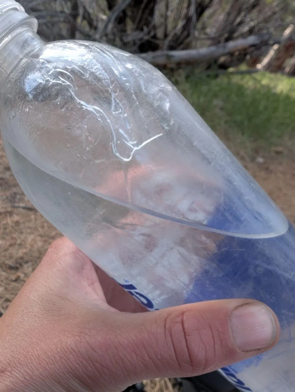 Main tenant une bouteille en plastique cabossée