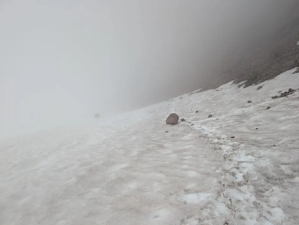 Pente enneigée disparaissant dans un épais brouillard