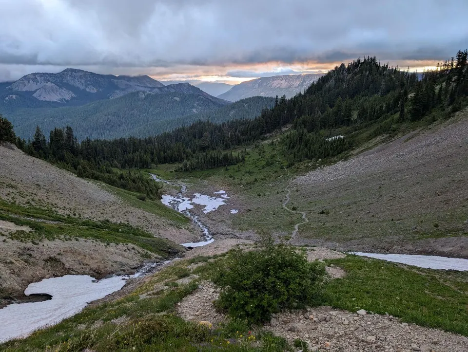 Vallon traversé par des ruisseaux de fonte sous un ciel sombre