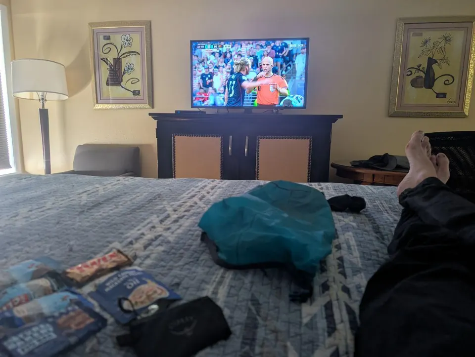Jambes allongées sur un lit face à un téléviseur