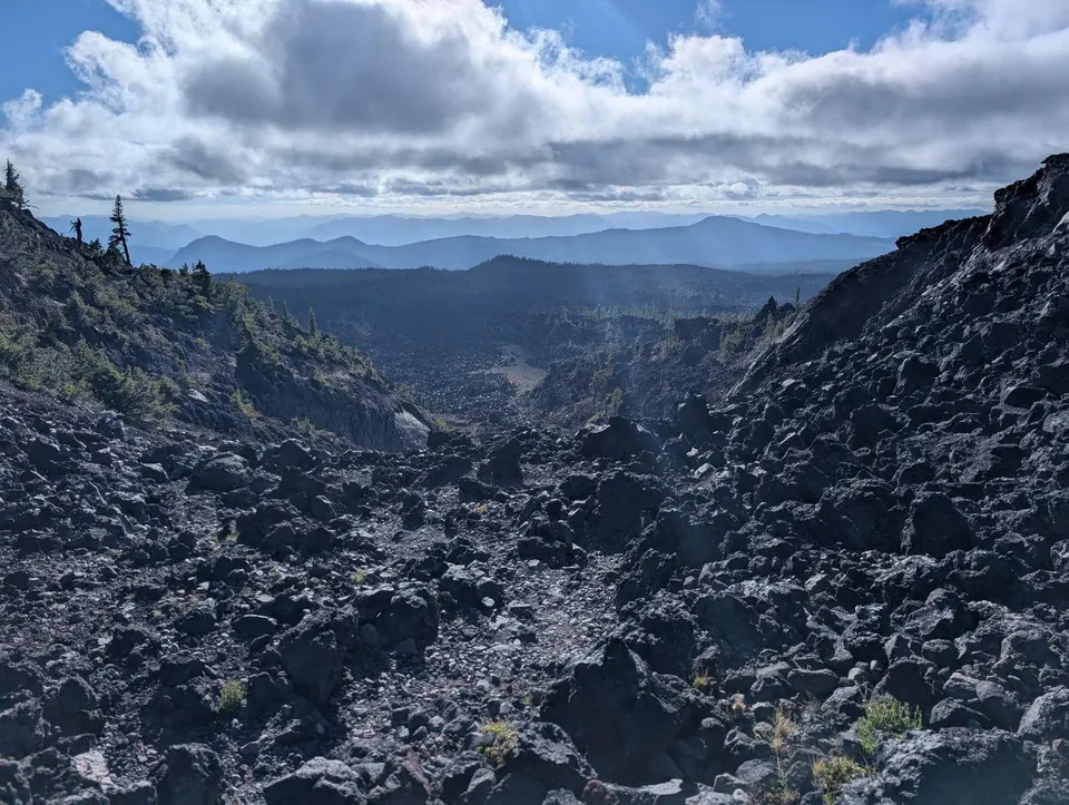 Vaste champ de lave noire entre deux versants montagneux