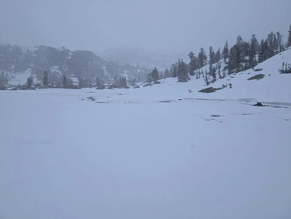 Lac gelé entouré de pentes enneigées dans le brouillard