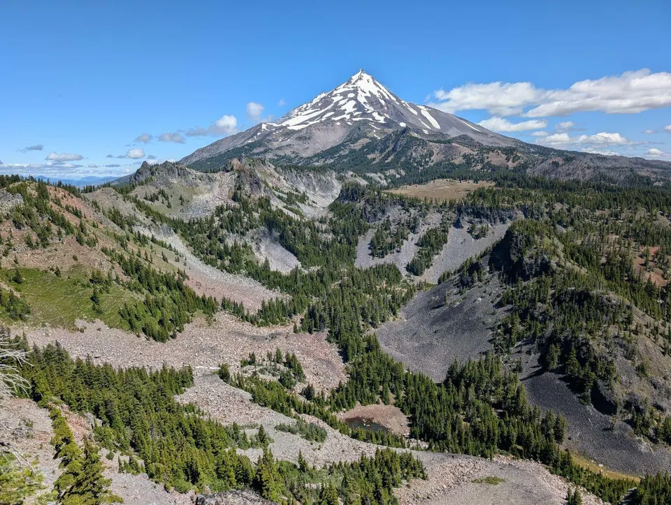 Sommet volcanique enneigé au-dessus d'une vallée boisée