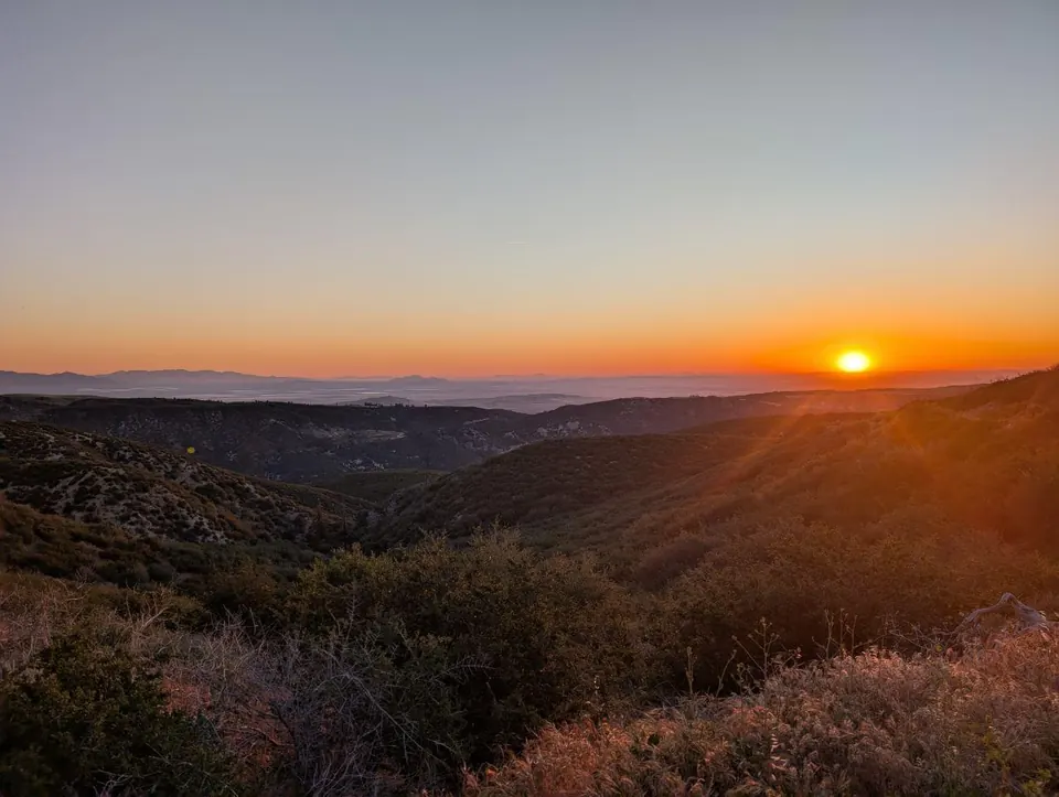 Soleil levant au-dessus de collines couvertes de broussailles
